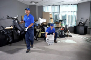 Two 1-800-GOT-JUNK? employees removing office chairs and debris from a commercial space in Fort Worth, TX.