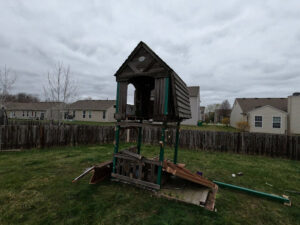 An old, broken wooden playset in a backyard, ready for removal by Indy Trash Guy in Fortville, IN.