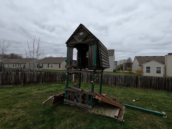 An old, broken wooden playset in a backyard, ready for removal by Indy Trash Guy in Fortville, IN.