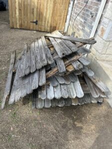 A pile of old, weathered wooden fence panels stacked for removal by Texas Junk Masters in Fort Worth, TX.