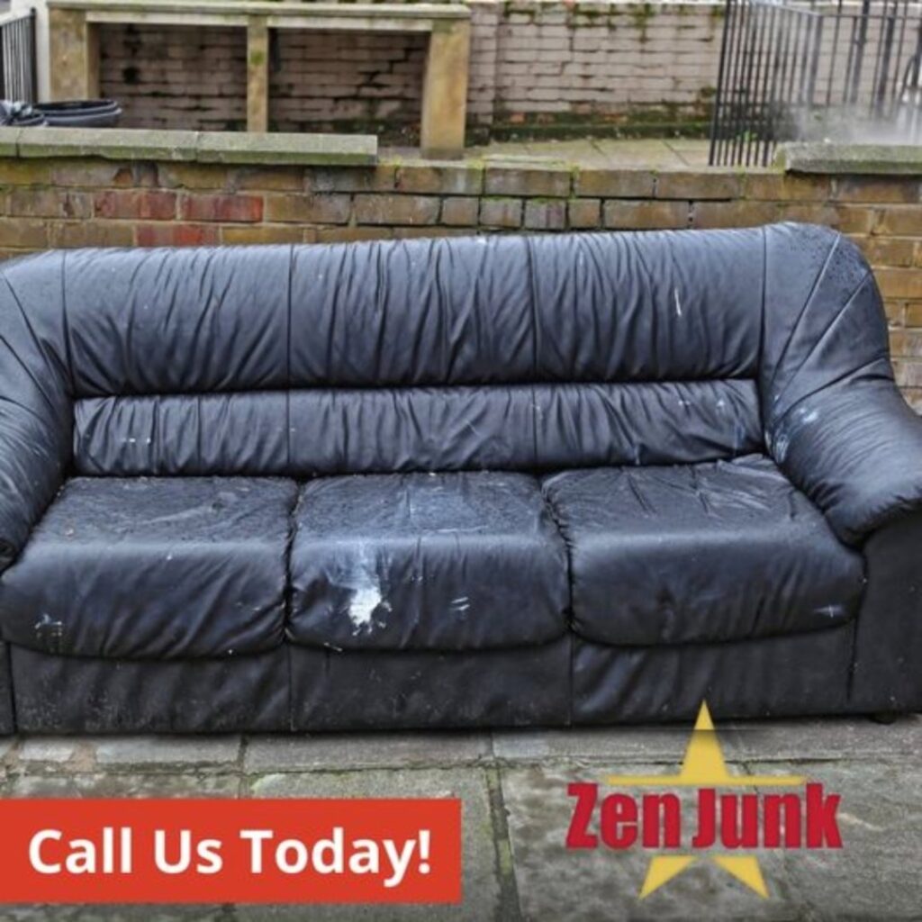 An old, worn black leather sofa placed outdoors, ready for general junk removal by Zen Junk in San Jose, CA.