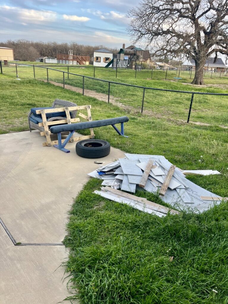 An outdoor area with old tires, wooden pallets, and other debris, ready for removal by NTX Haul Away Junk Removal in Fort Worth, TX.
