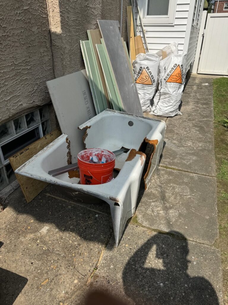 A pile of outdoor furniture, including an umbrella and chair, along with trash cans, ready for High Speed Junk Removal in Levittown, PA.