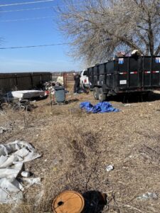 A large outdoor junk pile being removed and loaded into a dump trailer by JT Junk Solutions in Austin, TX.
