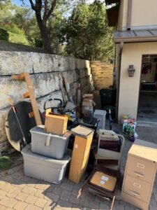 An outdoor pile of various items including boxes, a filing cabinet, and bins, ready for Junk King removal in Austin, TX