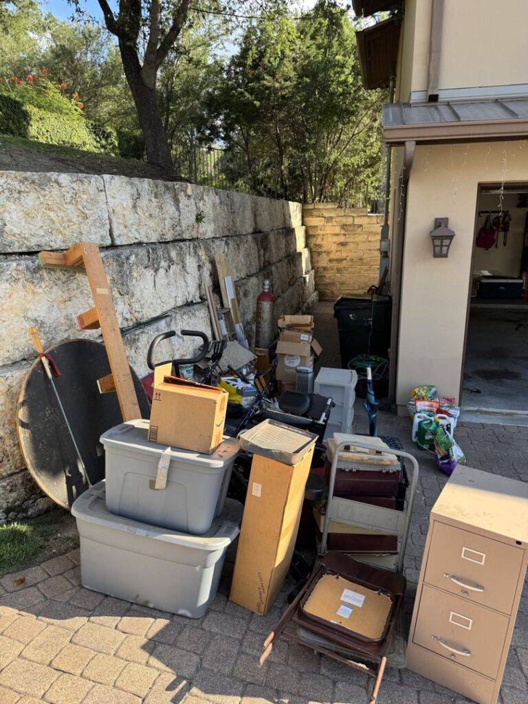 An outdoor pile of various items including boxes, a filing cabinet, and bins, ready for Junk King removal in Austin, TX
