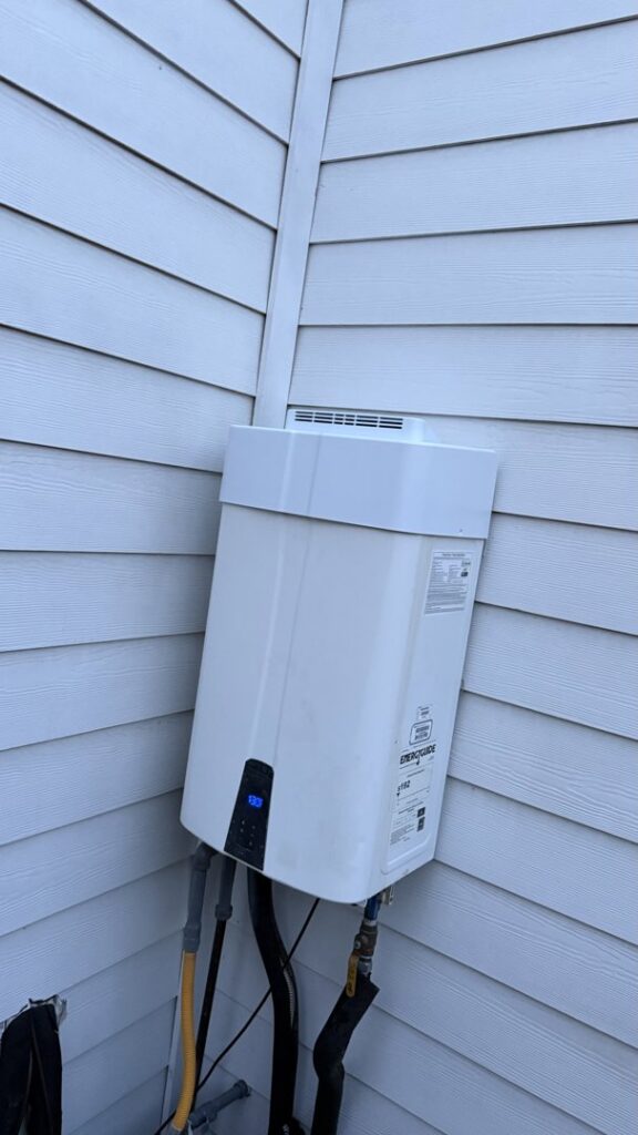 An outdoor tankless water heater installed on the corner of a house by Economy Plumbing Services in Austin, TX