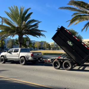 A silver pickup truck with a raised dump trailer, ready for junk removal, for SD Junk Takers Hauling and Junk Removal in San Diego, CA.
