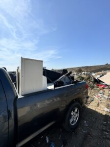 A pickup truck hauling a refrigerator and other debris to a landfill, demonstrating Johan's Junk Removal service in San Diego, CA.