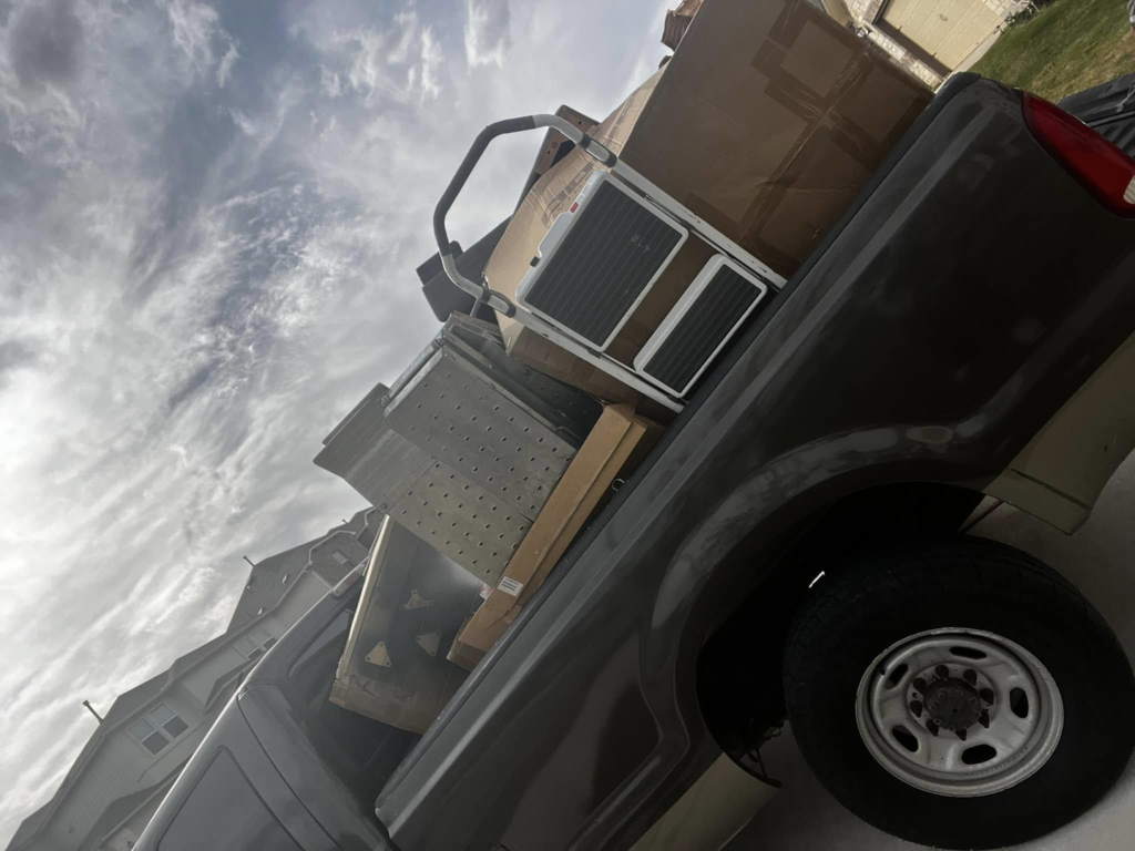 A pickup truck loaded with cardboard boxes and an old appliance for removal by ONLY Junk Removal Services in Austin, TX