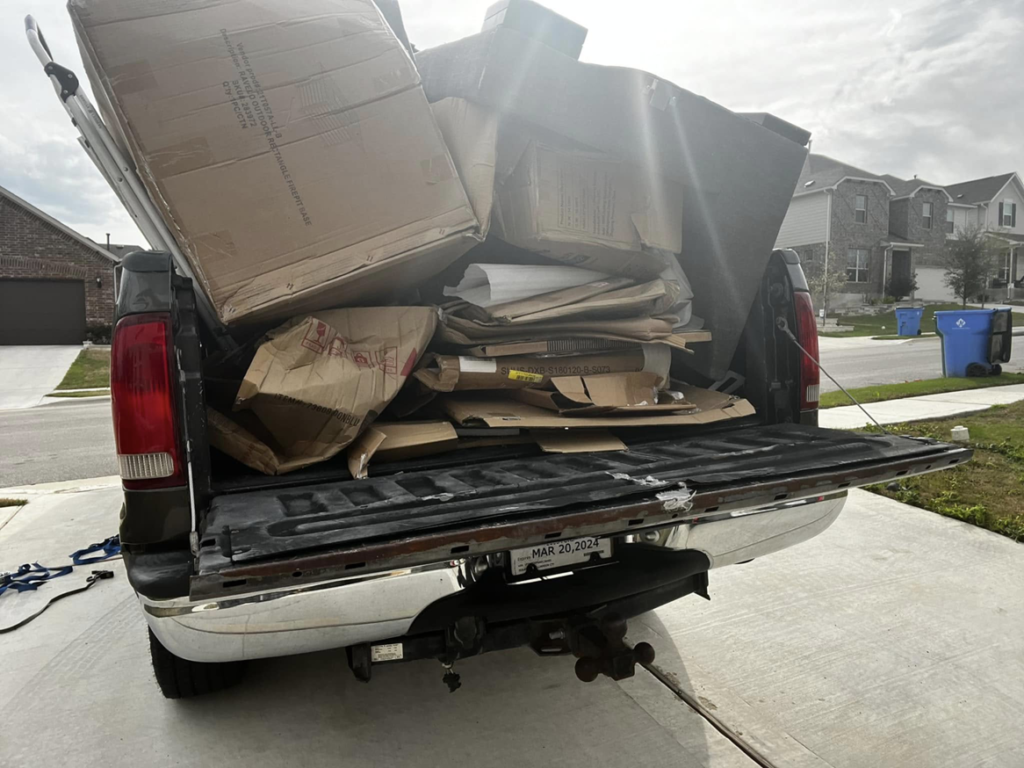 A pickup truck loaded with various cardboard boxes for removal by ONLY Junk Removal Services in Austin, TX