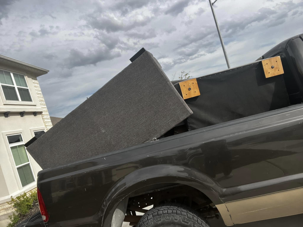 A pickup truck loaded with a large furniture frame for removal by ONLY Junk Removal Services in Austin, TX