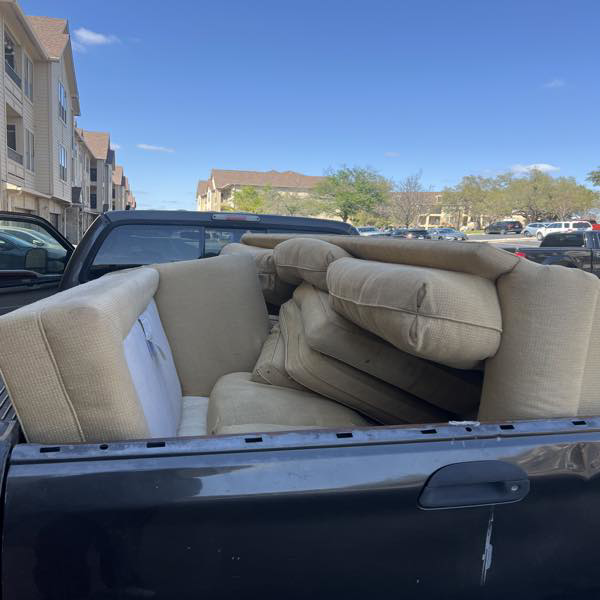 A pickup truck loaded with sofa cushions and furniture for removal by ONLY Junk Removal Services in Austin, TX