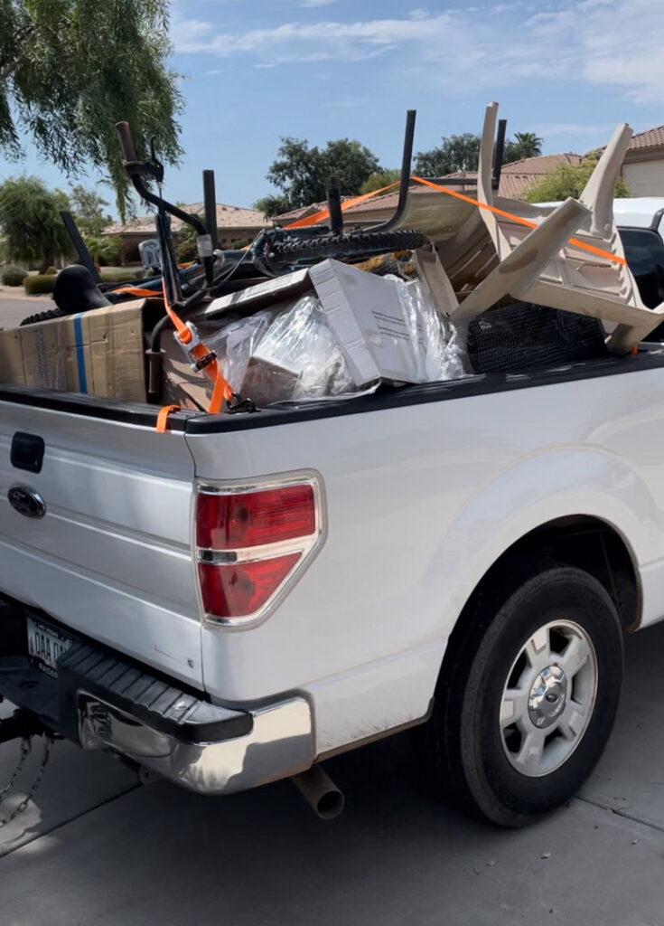 A Minutemen Junk Removal pickup truck loaded with a bicycle, chairs, and boxes, secured for transport in Phoenix, AZ.