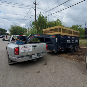 A McMillian Junk Removal pickup truck towing a trailer filled with debris in Houston, TX