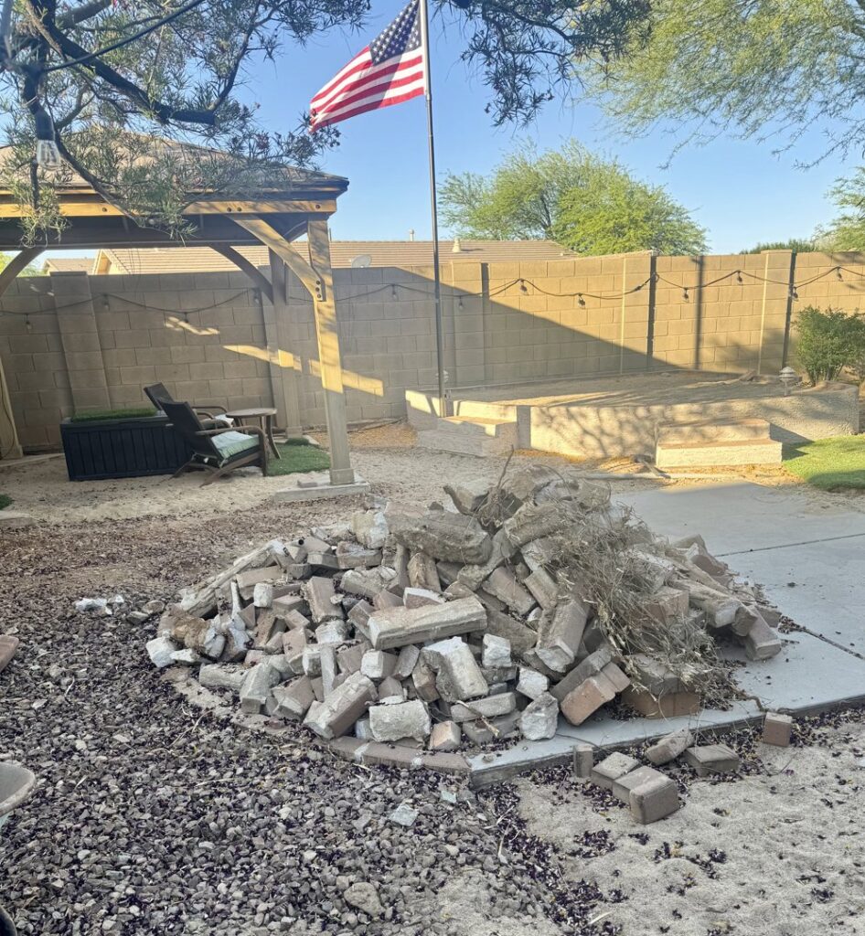A large pile of bricks and yard debris in a backyard, ready for removal by North Valley Junk Removal in Phoenix, AZ.
