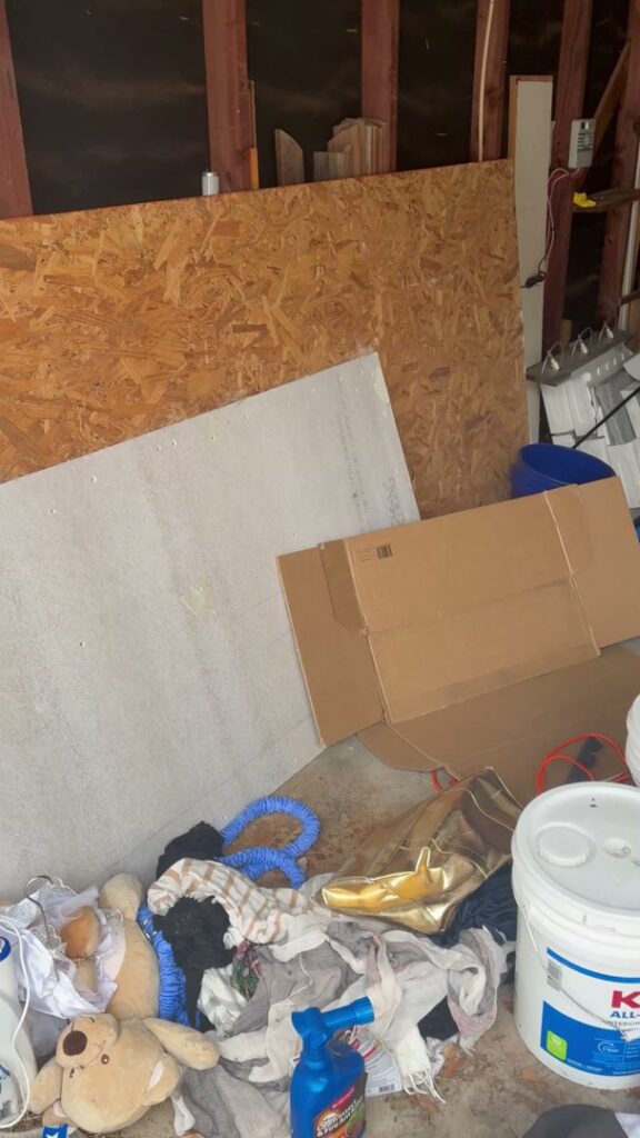 A pile of clothes, boxes, and miscellaneous items in a garage, ready for junk removal by Handymen Junk Removal in Houston, TX.