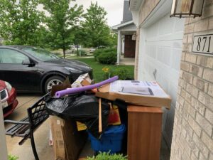 A pile of household junk and boxes placed outside a garage for removal by Indy Trash Guy in Fortville, IN.