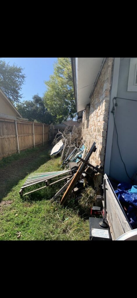 A pile of various junk and debris, including wood and brush, along a fence line for Firefighter Junk Removal in Austin, TX.