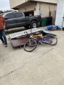 A pile of junk including a bicycle and a dresser on a driveway for Fred's Junk Removal in Chula Vista, CA.