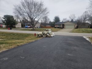 A large pile of rolled-up old carpets on a driveway, ready for junk removal by Junk Fellas LLC in Columbus, OH.