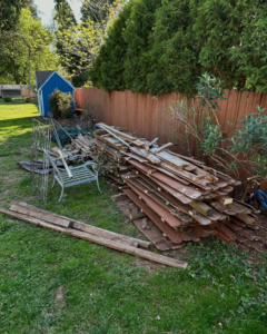 A large pile of old wooden fence panels and yard debris in a backyard, ready for junk removal by Nolen's Junk Removal in Feasterville-trevose, PA.