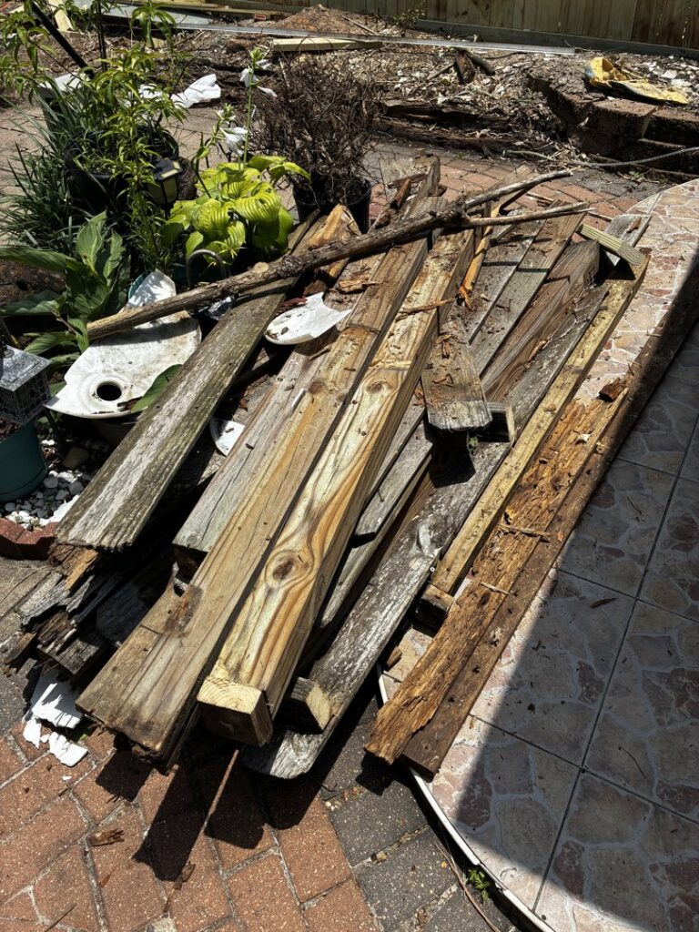 A pile of old wooden planks and construction debris on a patio, ready for removal by Handymen Junk Removal in Houston, TX.