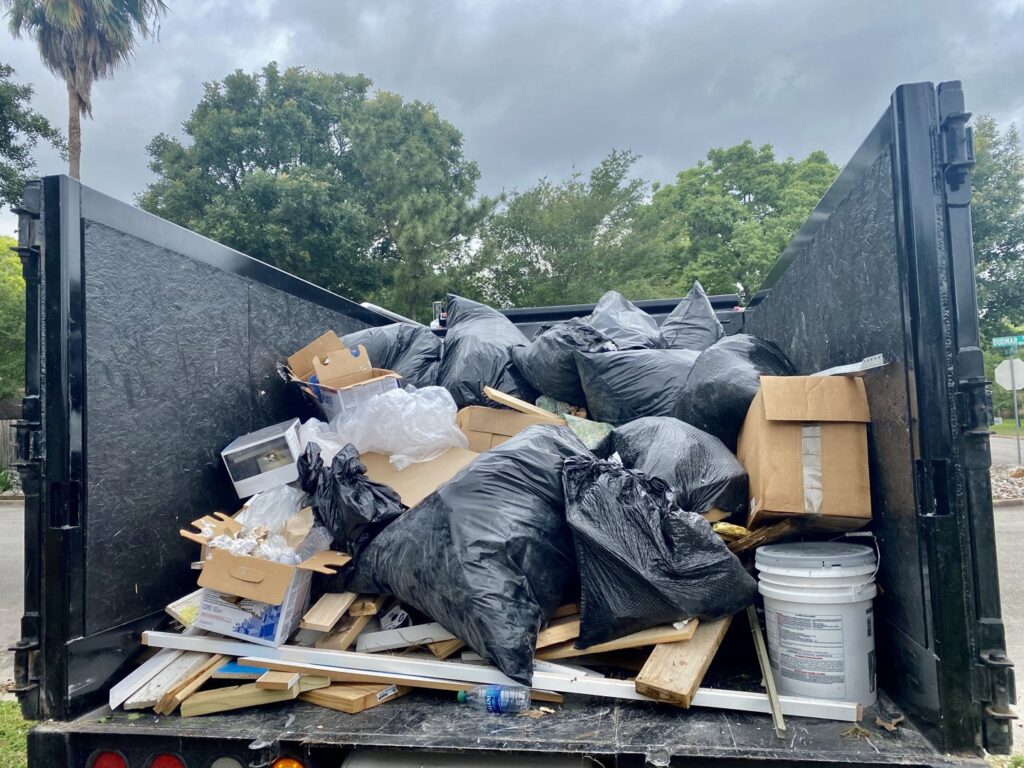 A large pile of wooden planks and debris in a residential backyard in Austin, TX, ready for junk removal.