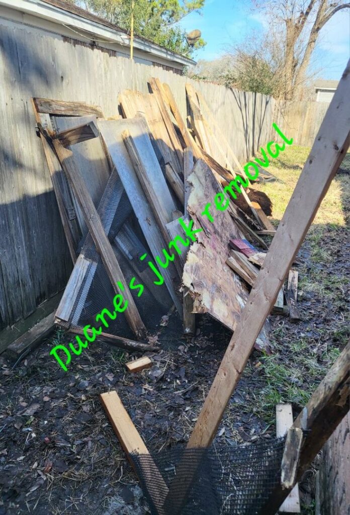 A large pile of old wood planks and debris in a backyard, ready for junk removal by Duane's junk removal LLC in Houston, TX.
