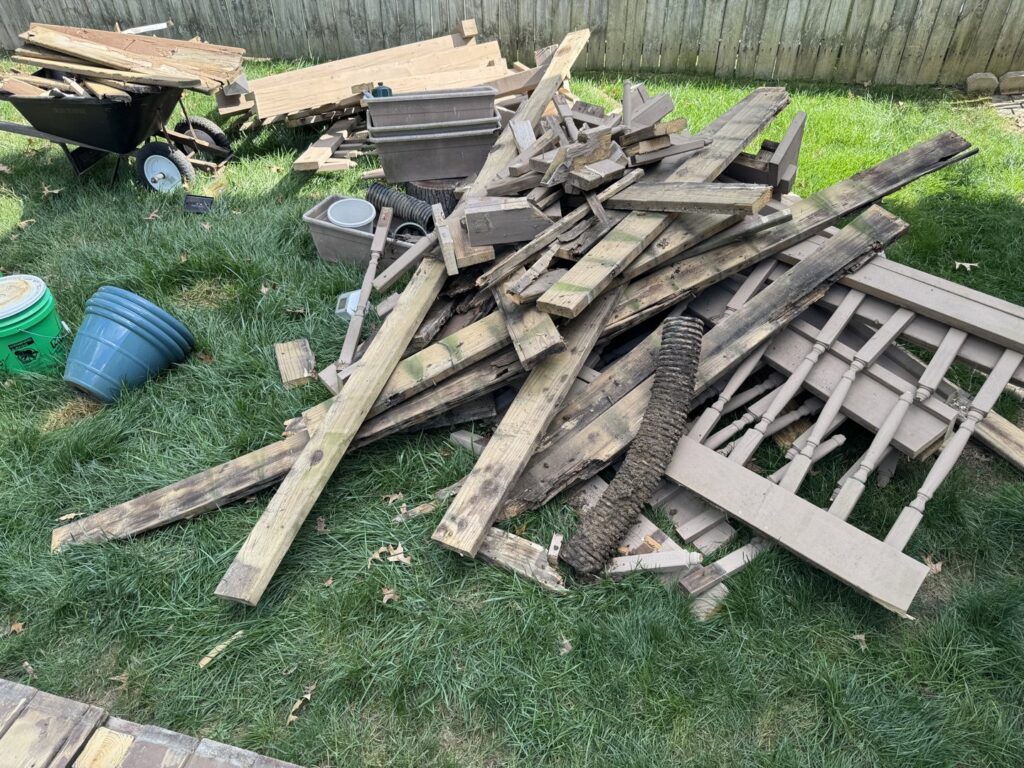 A pile of wooden planks, fence pieces, and other debris on the grass, ready for removal by Junk Removal of Hancock County in Indianapolis, IN.