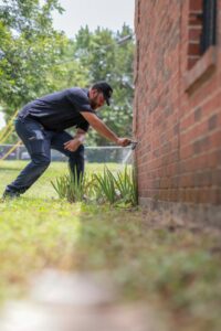 A plumber from Dallas Plumbing Company checking an outdoor spigot on a brick house in Dallas, TX.