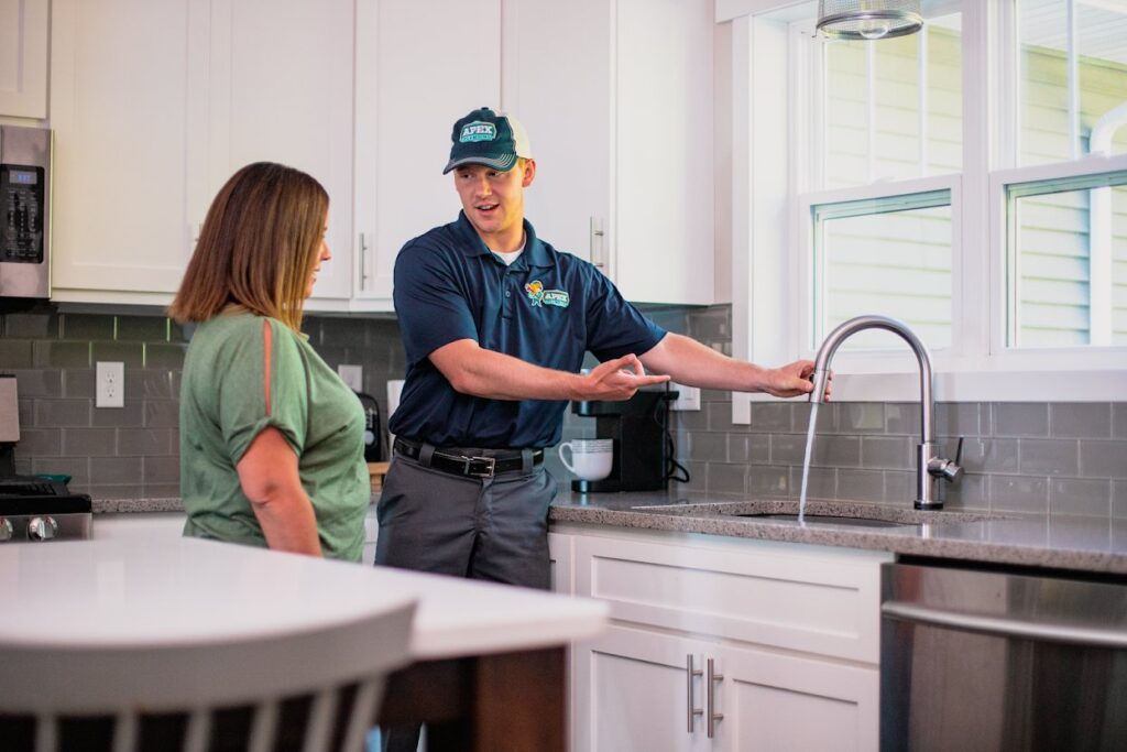 An Apex Pros Plumbing, Electric, Heating, and Air plumber consulting with a customer about a kitchen sink in Columbus, OH.