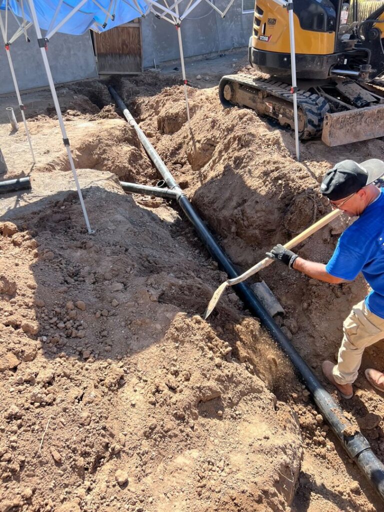 A plumber from Plumbing Services Inc. digging a trench for pipe installation or repair in San Diego, CA.