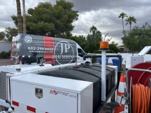 A plumber from JP Plumbing performing drain snaking in a commercial kitchen, clearing clogs in Phoenix, AZ