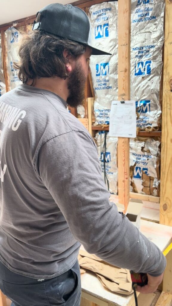 A Molberg Plumbing technician inspecting a remodel site with exposed walls in Ft Worth, TX