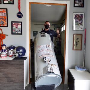 A plumber from JG Water Heaters, Filtration and Plumbing moving a new water heater for installation in San Diego, CA