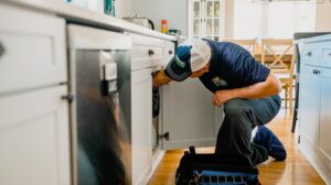 An Apex Pros Plumbing, Electric, Heating, and Air plumber repairing a kitchen sink drain in Columbus, OH.