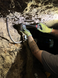 A Molberg Plumbing technician repairing pipes in a confined crawl space in Ft Worth, TX