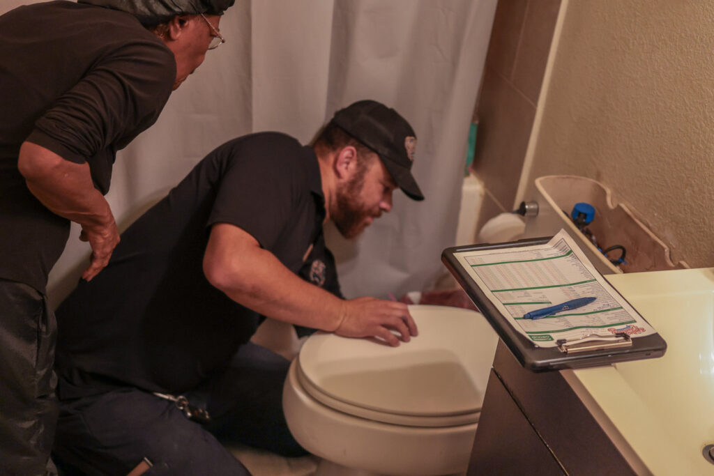 A plumber from Dallas Plumbing Company repairing a toilet in a residential bathroom in Dallas, TX.