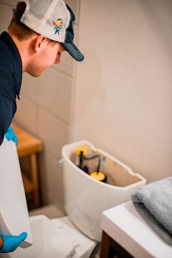 An Apex Pros Plumbing, Electric, Heating, and Air plumber repairing a toilet tank in Columbus, OH.