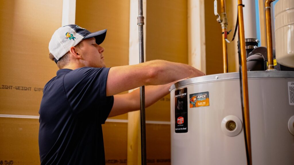 An Apex Pros Plumbing, Electric, Heating, and Air plumber servicing a water heater in Columbus, OH.