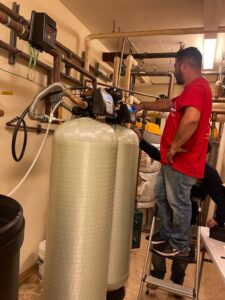 A plumber from Plumbing Services Inc. installing or servicing a water filtration system in San Diego, CA.