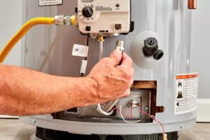 A plumber's hand connecting a gas line to a water heater during service by JG Water Heaters, Filtration and Plumbing in San Diego, CA