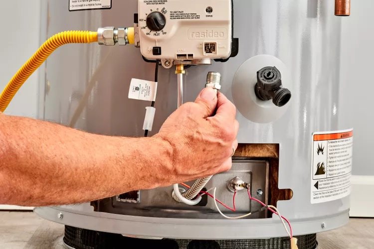 A plumber's hand connecting a gas line to a water heater during service by JG Water Heaters, Filtration and Plumbing in San Diego, CA