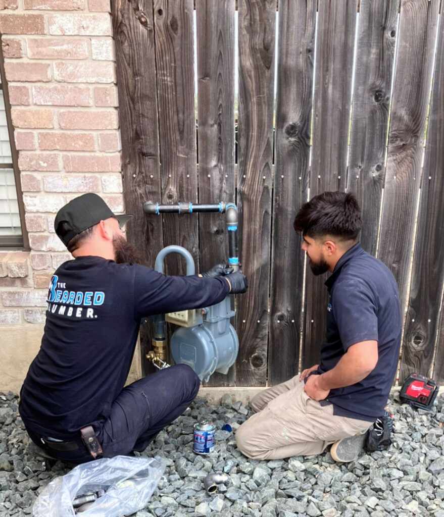 Two plumbers from The Bearded Plumber working on a gas line and meter outside a home in San Antonio, TX.