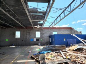 Interior of a building with a damaged roof and debris on the floor, indicating a post-demolition or disaster cleanup by IHaul Austin in Austin, TX.