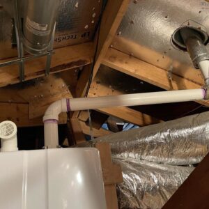 Newly installed PVC drain or vent pipes in an attic space, showcasing plumbing installation by Tribeca Plumbing in Dallas, TX.