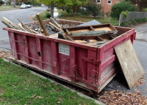 A red dumpster filled with various junk and debris on a residential street, provided by Eagle Dumpster Rental in Philadelphia, PA.