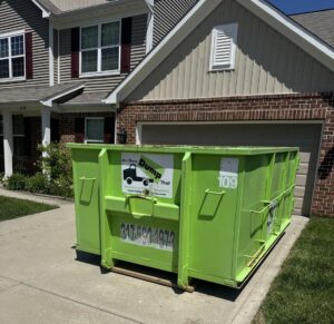 A Bin There Dump That green dumpster positioned on a residential driveway for efficient junk removal in Indianapolis, IN.
