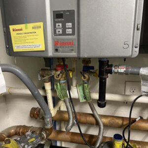 A Rinnai tankless water heater unit with control panel and plumbing connections, serviced by Tribeca Plumbing in Dallas, TX.